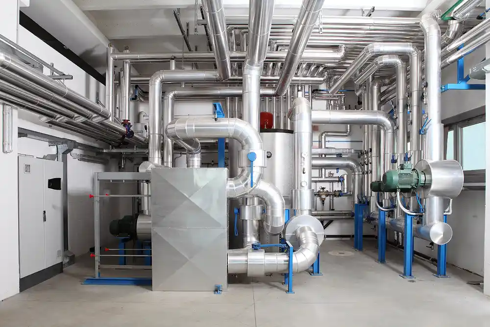 A complex network of shiny metal pipes and industrial machinery in a clean, white utility room. The scene conveys a sense of efficiency and functionality.